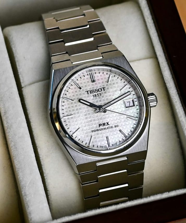 Tissot watch with silver case and mother-of-pearl dial on a wooden surface
