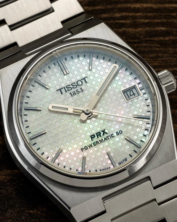 Tissot watch with silver case and mother-of-pearl dial on a wooden surface