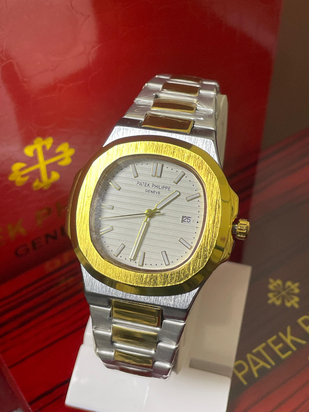 Two-tone watch with gold and silver band on a red background with Patek Philippe branding.