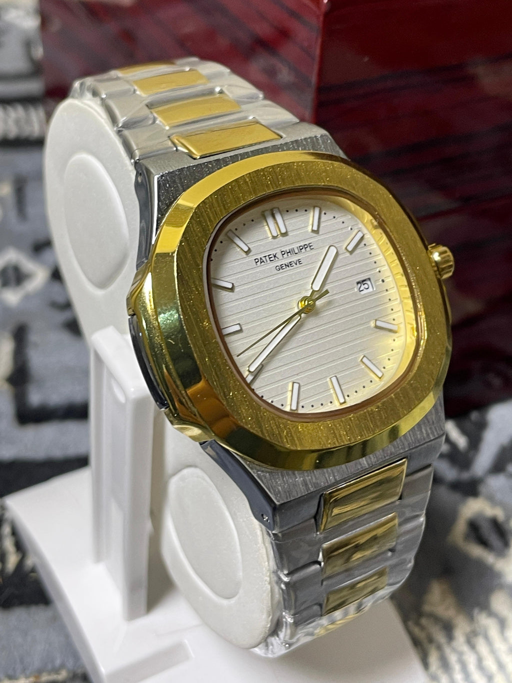 Gold and silver watch on a white stand with a blurred background