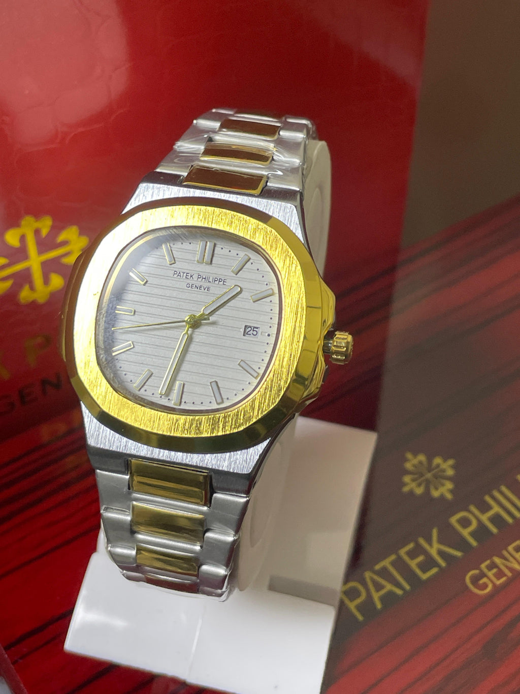 Two-tone Patek Philippe watch on a red and gold background